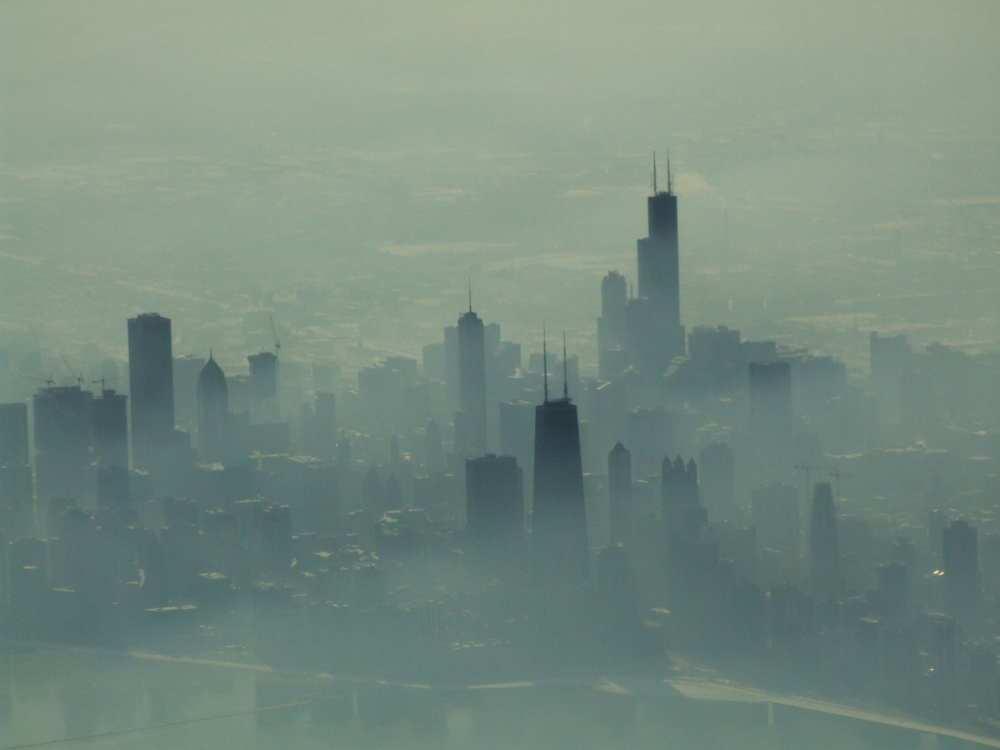 A photo taken from the plane of the Chicago skyline, shrouded in fog.