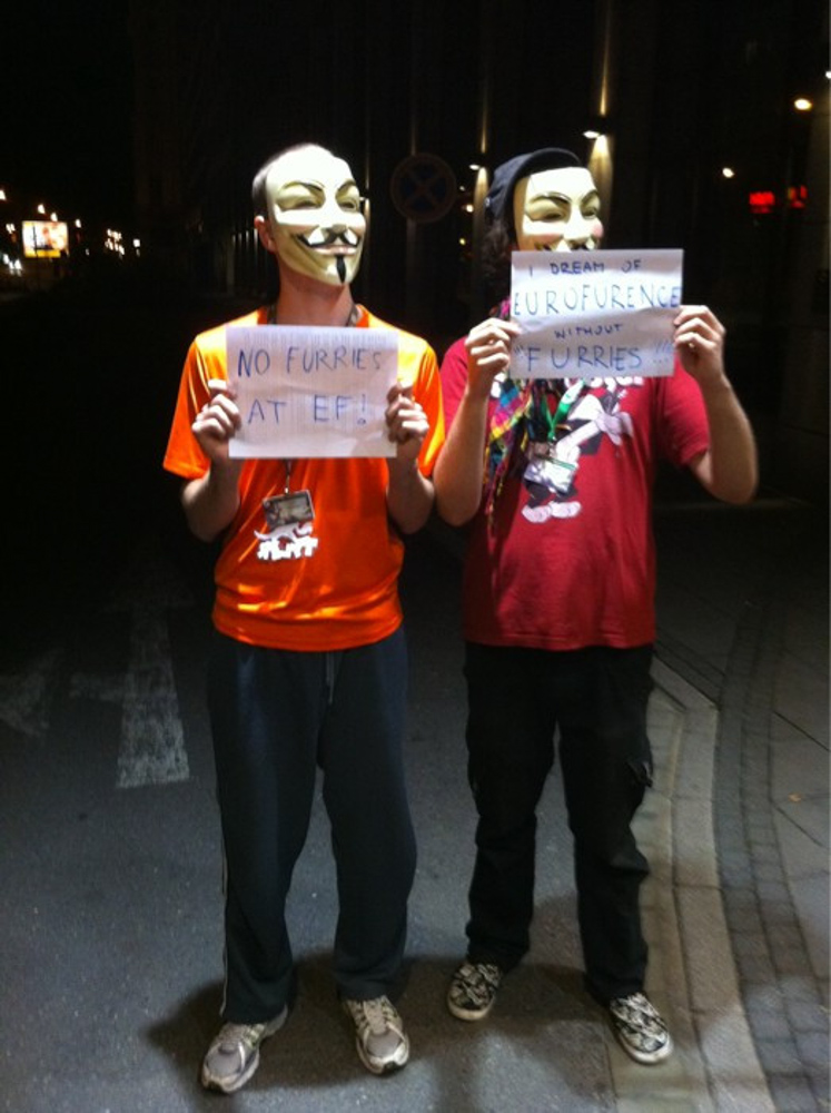 Two anonymous people self-ironically protesting against furries while having their badges clearly visible.