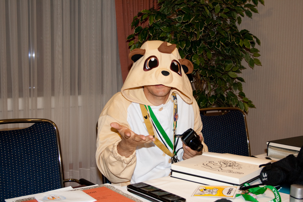Titash in the Artist Lounge, wearing a meerkat kigurumi.