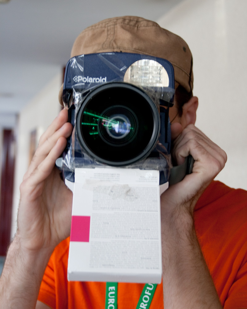 A Polaroid 600 type camera with a wide-angle lens taped to it.