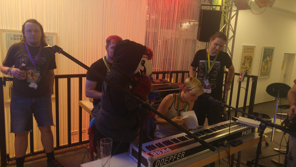 Four humans and a parrot making music together on a stage in the lobby