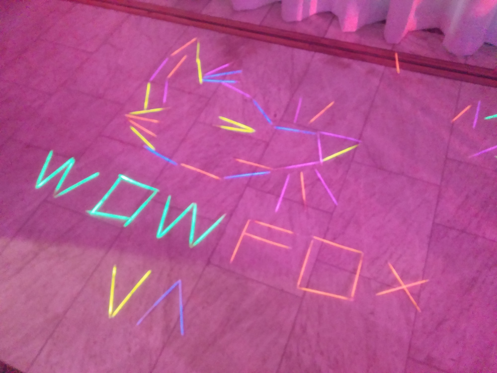A fox head laid out with glowsticks and a caption "WOW FOX", also laid out with glowsticks